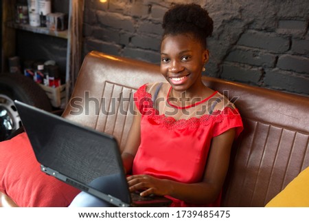 beautiful young african woman with laptop on sofa