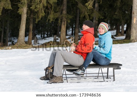 young couple having fun on the sledge in the winter