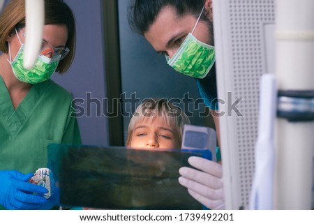 Young female and male dentists showing to their patient an X-ray picture of her teeth