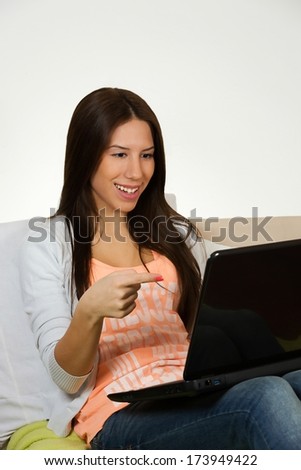 Cute young woman, surfing the internet, lying on her bed.