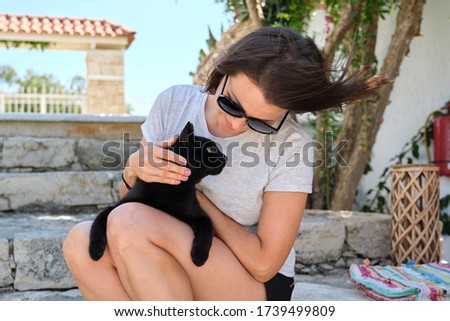 Happy woman with black cat, outdoor portrait of owner and pet.