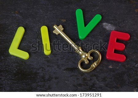 Antique key on a slate background with the word live in letters