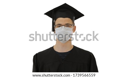 Student in gaduation gown and face mask stumbling on white background.