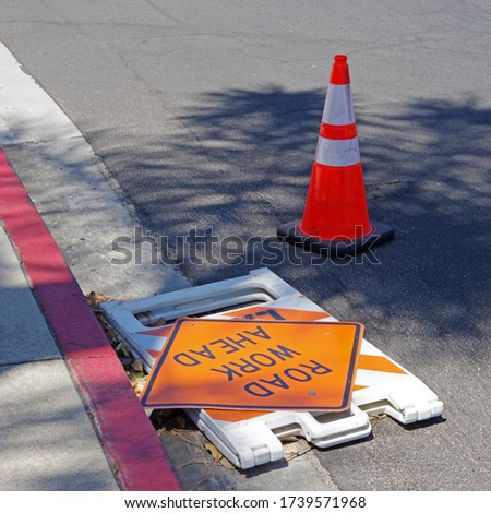 traffic cone and collapsed road work sign on a street