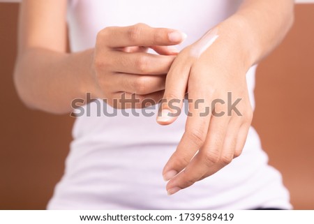 applying moisturizer lotion on her hand for efficacy testing of natural organic skincare products in laboratory.
