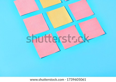 Two yellow and frame of pink square blank paper stickers on blue background. Copy space
