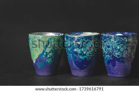Close up picture of set glasses from ceramic in green dark blue shades on dark background as tableware restaurant wallpaper concept with special custom design of sea color