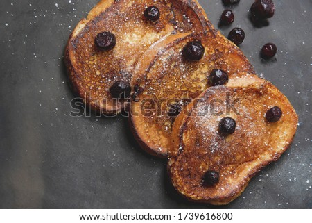 Close up picture of traditional sweet homemade breakfast from toasted bread with red berries and white powder on black background as food photography wallpaper concept for restaurant 