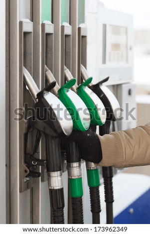 vehicle and fuel concept - close up of male hand holding fuel pump at fuel station