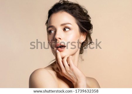 Young woman with pure skin feeling fear, wonder, surprise or shock beauty portrait on beige copy space. Pretty millennial girl with bare shoulder open mouth.  Royalty-Free Stock Photo #1739632358