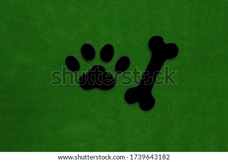 A dog's paw print, a black bone on a green background. Pet, veterinary.