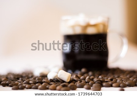 A lot of roasted coffee beans on a white background a cup of marshmallows foam