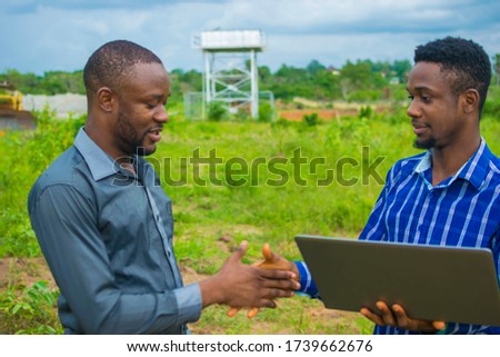 young black men discussing some business plans to be executed on a farmland