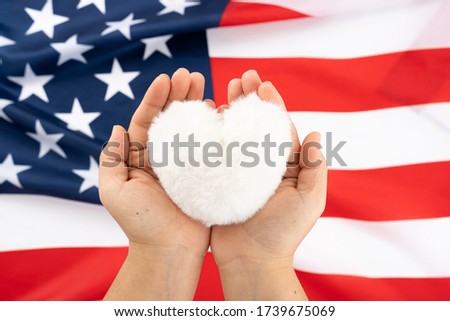 US American flag with hand holding white heart shape on white background. For USA Memorial day, Presidents day, Veterans day, Labor day, Independence or 4th of July celebration. Copy space for text.