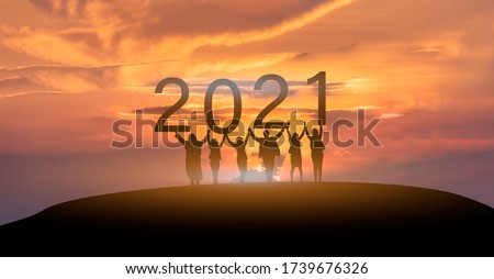 Happy new year 2021, Silhouette of 2021 letters on the mountain with business people raised arms in teamwork concept at sunrise.  Royalty-Free Stock Photo #1739676326