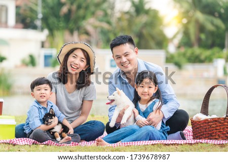 An Asian family plays with a Shiba Inu dog. Family has father, mother and son, daughter. Picnicking in the garden. Royalty-Free Stock Photo #1739678987