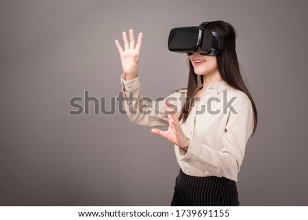 beautiful woman is using virtual reality on gray background 
