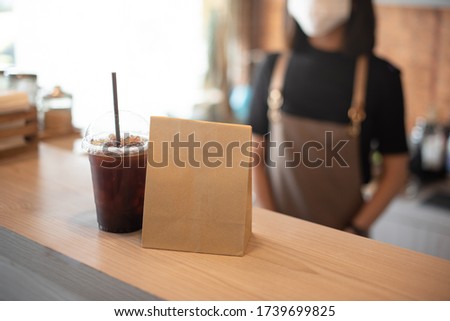 Barista  in apron and face mask standing  behind counter bar ready to give Coffee Service at the modern coffee shop, Modern cafe business, Social distancing concept.  Royalty-Free Stock Photo #1739699825