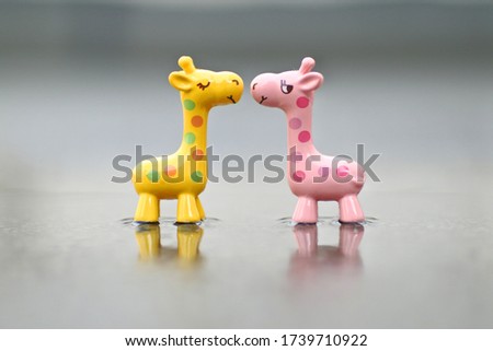 Wooden toys yellow and pink giraffe photographed with the effect of puddles and blurred background. Close up photo.