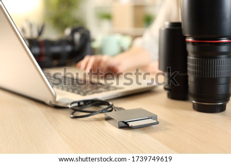 Close up of photographer woman hands transfering files from memory card to laptop on a desk at home