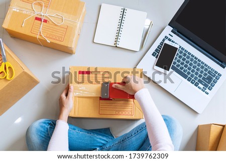 Young Asian business entrepreneur sealing a box with tape. Preparing for shipping, Packing, online selling, e-commerce concept. Top view, copy space Royalty-Free Stock Photo #1739762309