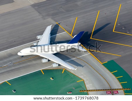Aerial view of large white unidentified aircraft in an international airport runway before take off. Airplane before departure with runway and taxiway signs. Airport yellow chevrons background.