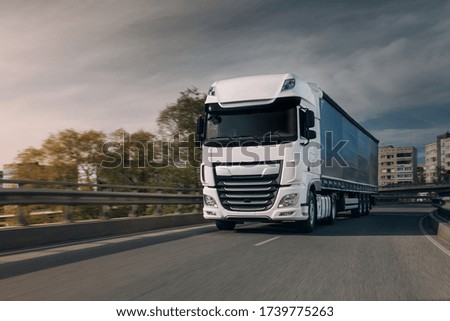Semi-truck with cargo trailer driving at the city streets. Fast-moving truck. Lorry drivers go fast on the highway. Lorry truck drivers go fast at the city center. Truck towing a trailer Royalty-Free Stock Photo #1739775263