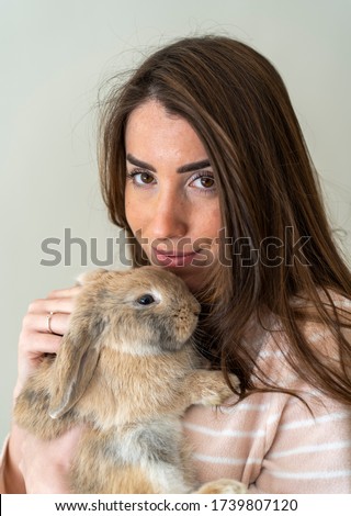 beautiful thin woman posing in a pair of children's pajamas with her pet rabbit