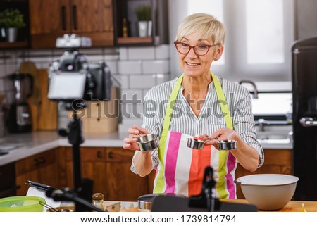 Elderly woman baking for her online streaming cooking channel. Older woman vlogging
