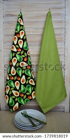Decorative green towel They weigh on a hook. Close up. Avocado towel For the house. The color of green Against a beige wall.