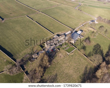 Aerial photo of an old abandoned farm building in the British North Yorkshire country side showing an old farm house along  side farmers fields in the winter time with bare trees