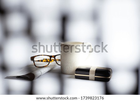 Cup of morning coffee, eyeglasses, wrapped gift box, newspaper with crossword on light background, soft focus. Happy Fathers Day, Business gift present concept