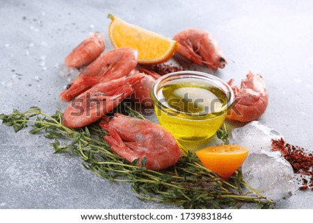 Seafood. Raw pink prawns shrimp on a white wooden board with lemon, thyme, tomato, spices and ice on a light grey background. Background image, copy space 