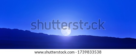 Beautiful Full Moon over the mountains. Moonrise in the mountains. Contour of the mountains and Disk of the moon.