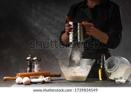 Chef works with flour. Bakery preparing bread and pastries. Freezing in motion.