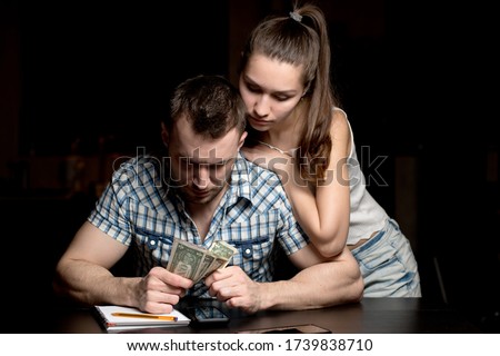 A young woman supports a man who counts the rest of the money at a difficult time, when the family hardly survives. The financial crisis in a young family