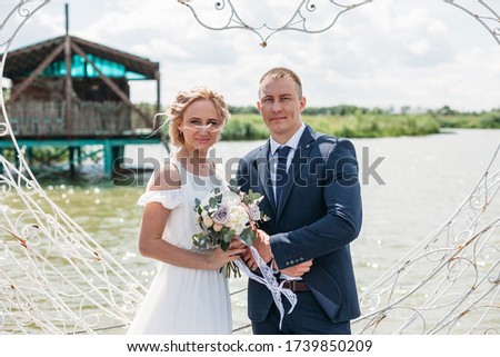 newlyweds embrace near the figure heart by the lake