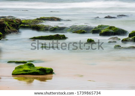 Photography of long exposure of the tide and algae on the rocks of the shore of Guincho Beach, Santa Cruz, Portugal.