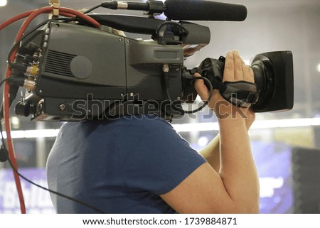 Videographer or television operator holding camera on his shoulder and taking a video