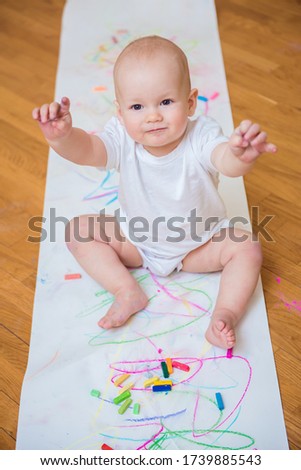 Little cute child with creativity draws with crayons at home on a sheet of white paper. The concept of children's early development of creativity