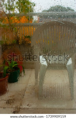 Blurry view of a chair on a rainy autumn day through a window