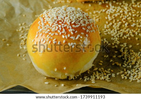 bun with sesame seeds on parchment paper