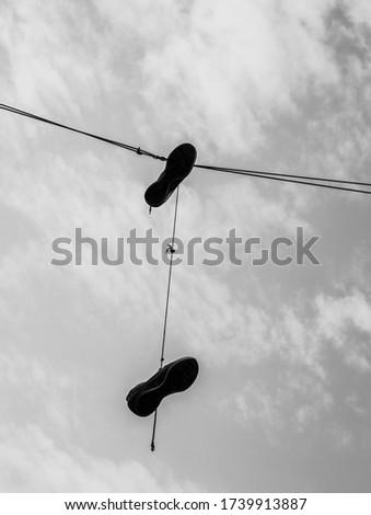 Black and white photo of a hanging shoes off a wire
