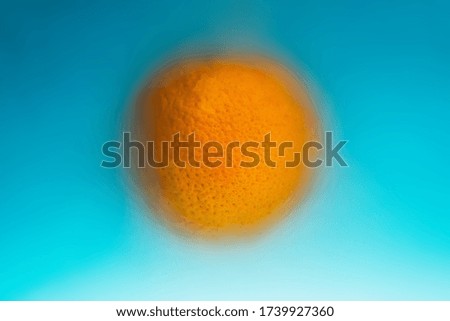 Orange fruit in bright blue muddy water, abstract background, minimalism.