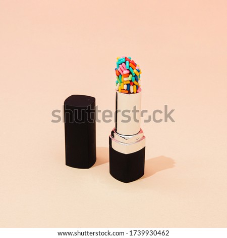 Creative concept with lipstick with colorful cake sprinkles. Minimal make up background.