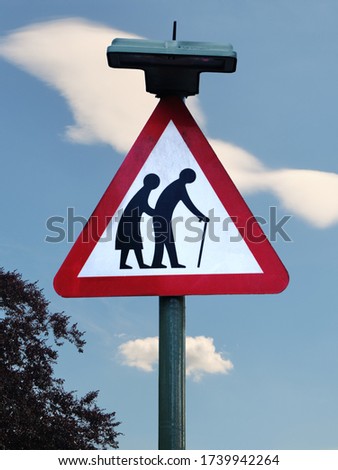 Elderly crossing sign on blue sky with white clouds