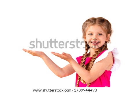A little girl with pigtails stretches out her hands and shows you a place to copy space on an isolated white background.