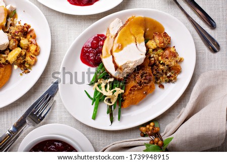 Festive Thanksgiving dinner table with plates of food, turkey and all the sides
