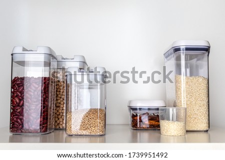 Clear Pantry Containers Filled with Non-Perishable Foods-- Dried Beans, Grains, Dried Peppers, Rice-- and Measuring Cup
