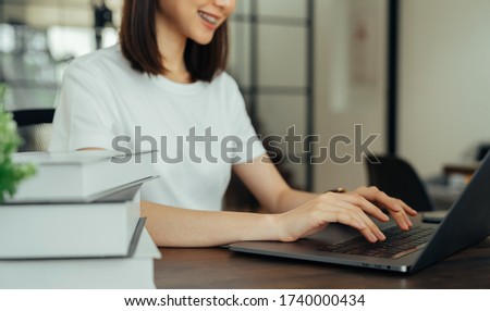 woman hand holding press the button on the keyboard laptop and stack of books.